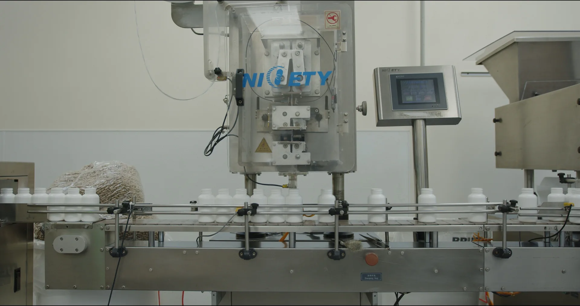 Automated capsule bottle filling line inside a Nutricel Labs manufacturing facility, bottles moving down a conveyor for labeling and packaging